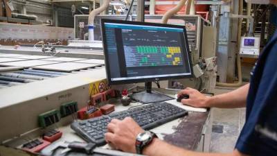 Un operario trabaja con un sistema informático en una fábrica cerámica.