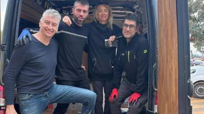 $!David junto a tres voluntarios en una furgoneta habilitada para el reparto.