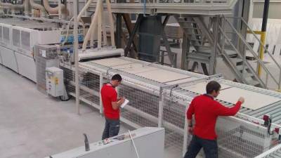 Dos operarios trabajan en una fábrica de azulejos.